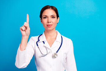Cheerful female doctor points up ready to guide you through a friendly professional health...