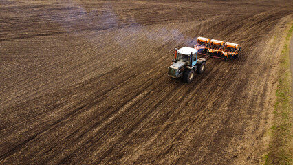 Aerial View of a Tractor Pulling a Seeder with Exhaust Smoke in a Tilled Field © Andrey