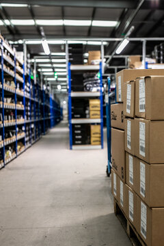 Modern warehouse interior featuring blue metal racking systems and vertical shelving designed to maximise storage space for industrial goods and spare parts. Stacked cardboard boxes ready for shipping