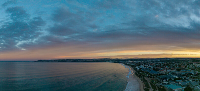 Aerial view of Hartenbos coastline with the calm ocean, sandy beach, and coastal town under a dramatic sunset sky Mossel Bay, Western Cape, South Africa.