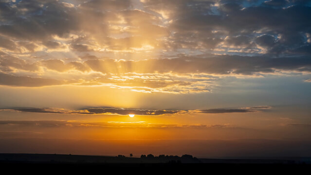 Dramatic golden sunset sky with layered clouds and glowing sunlight rays