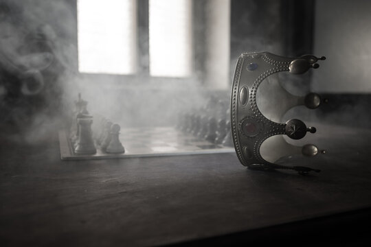 Beautiful crown miniature on chessboard. chess board game concept of business ideas and competition and strategy ideas concept. Chess figures on a dark background with smoke and fog. Selective focus