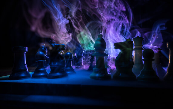 Chess board game concept of business ideas and competition. Chess figures on a dark background with smoke and fog.