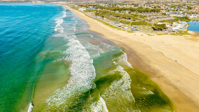 Aerial view of Hartenbos beach with turquoise ocean waves, golden sand, and coastal houses in Mossel Bay, Western Cape, South Africa.