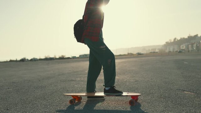 Young skater girl skateboarding on a longboard at sunset