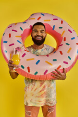 Naklejka premium Vibrant young man enjoying a sunny day with a playful donut float and refreshing drink
