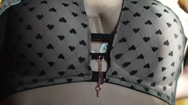 Woman bra removing, close-up of woman removing black lace heart-patterned bra in an intimate moment