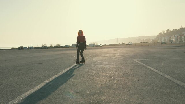 Young woman with pink hair rollerskating at sunset