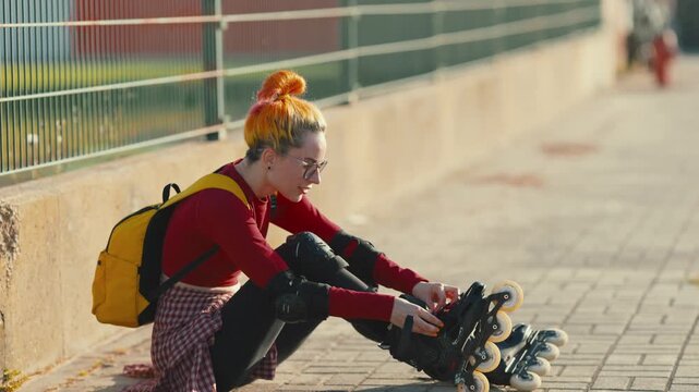 Stylish woman preparing for roller skating at sunset