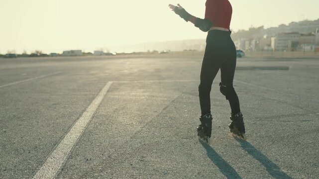 Young woman skating backwards on rollerblades at sunset