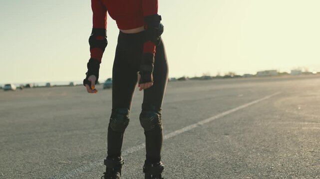 Young woman inline skating on asphalt during sunset