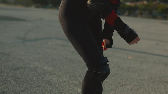 Woman rollerblading on asphalt during sunset