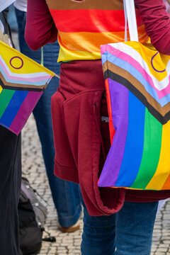 People celebrate LGBTQ pride with flags and colorful clothing in a public event at a city street