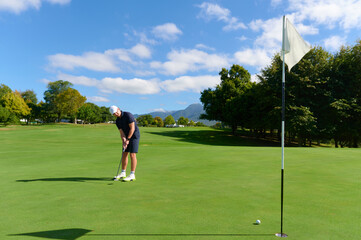Obraz premium Man putting golf ball on green course