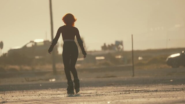 Silhouette of a woman rollerblading during a golden hour sunset