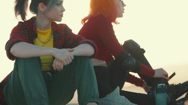 Two female skaters preparing rollerblades outdoors at sunset