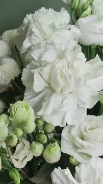 Vertical 4K macro of white eustoma bouquet. Close-up of fresh lisianthus flowers, carnations, and chrysanthemums with green buds.