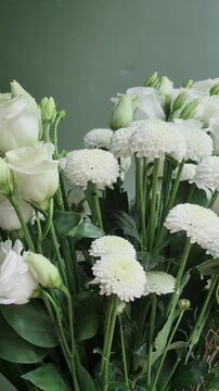 Vertical 4K macro of white eustoma bouquet. Close-up of fresh lisianthus flowers, carnations, and chrysanthemums with green buds.