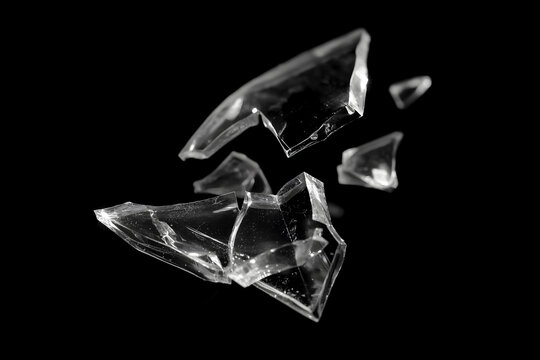 Broken transparent glass shard isolated on a black background, with sharp cracked edges, glossy reflections, and dramatic high-contrast studio lighting.