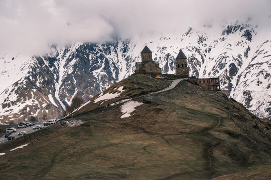 Gergeti Trinity Church standing on a hill under snowy Caucasus peaks in Kazbegi, Georgia