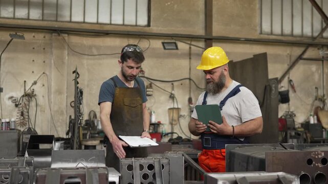 Industrial workers discussing project plans in a metal factory