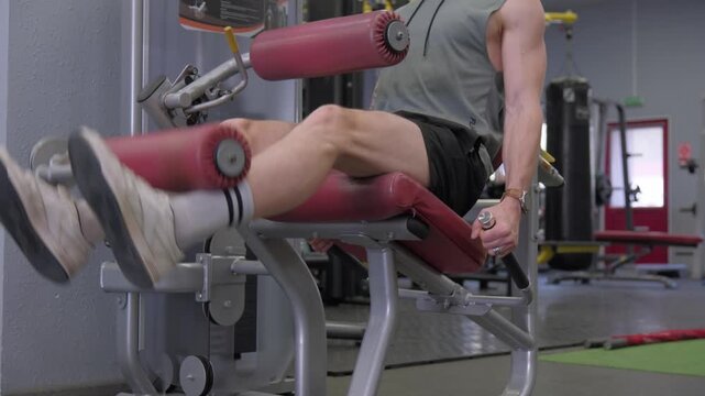 Man using leg extension machine in gym for workout at fitness center