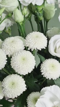 Vertical 4K macro of white eustoma bouquet. Close-up of fresh lisianthus flowers, carnations, and chrysanthemums with green buds.