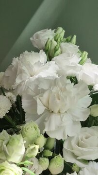 Vertical 4K macro of white eustoma bouquet. Close-up of fresh lisianthus flowers, carnations, and chrysanthemums with green buds.