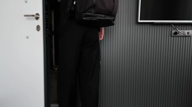 Young man leaving apartment with backpack before work, daily routine and repetitive office lifestyle, commuting fatigue, emotional burnout and modern work pressure concept