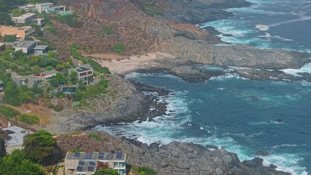 A telephoto aerial view of the coast of Pite, Valparaiso, Chile, and its luxurious and exclusive mansions high up on rocky mountains, seen through the clouds