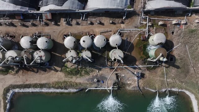 Aerial view of industrial wastewater treatment ponds with storage tanks and aeration systems