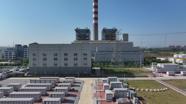 Thermal power plant complex with cooling towers, smokestacks, and rows of equipment under clear blue sky