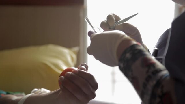 A nurse draws blood into glass test tubes from a man. Wearing rubber gloves, she transfers the blood from a plastic tube into the test tubes with great expertise.