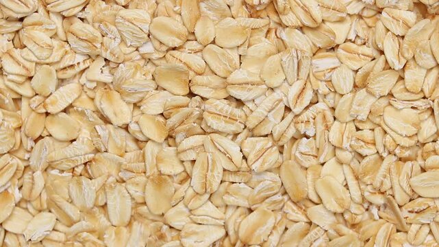 Top view of a slowly rotating pile of whole grain rolled oats.