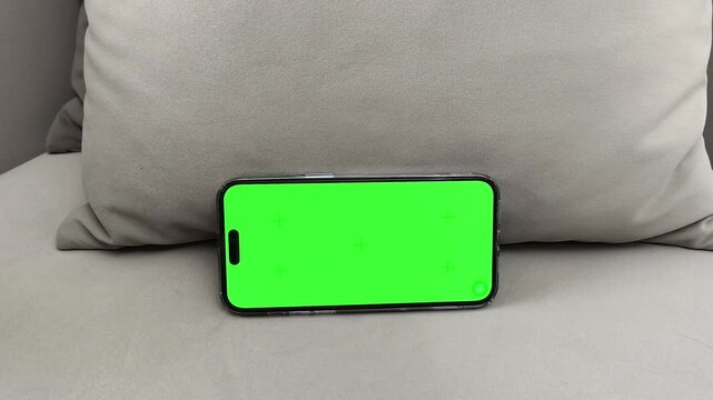 Smartphone with green screen rotates from vertical to horizontal and finger taps play at center. Hand switches orientation and starts video on chroma display. Concept streaming, mobile