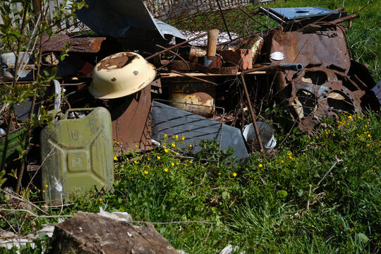 Old green jerry can and scrap metal in the backyard of a rural house