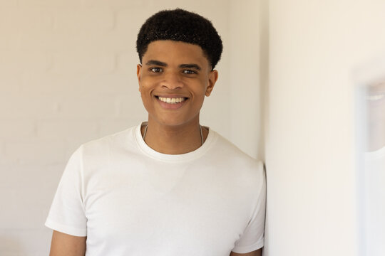 African American man smiling at camera in portrait studio wearing white T-shirt and chain