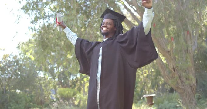 African American man running forward swinging arms holding diploma in gown celebrating in park