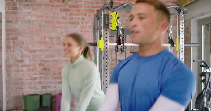 Diverse workout partners performing kettlebell swings starting from hip hinge for power in home gym