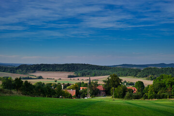 Tranquil green hills and charming village scenery. Sunshine bathes rolling pastures dotted with cottages and lush trees © Igor Syrbu