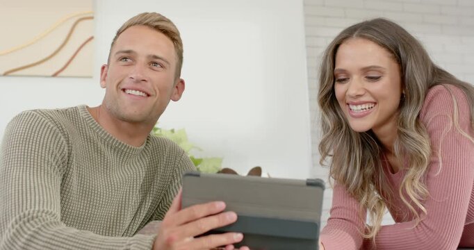 Diverse couple responding to tablet content, watching folio screen and discussing at countertop