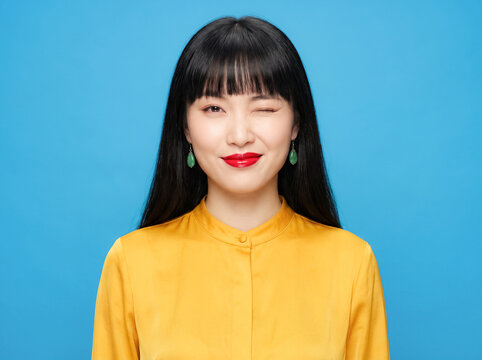 East Asian woman portrait beauty soft blue background twenties ivory yellow blouse relaxed front pose showing clean beauty elegance for skincare cosmetics campaigns diversity identity
