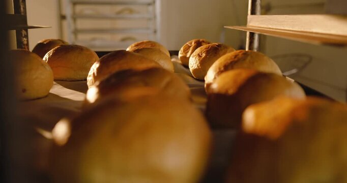 Camera is pulling back as parchment tray is sliding, revealing dozen golden rolls on metal rack