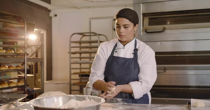 Female coworkers starting from flour bowl, scooping, shaping dough at steel prep table for baking