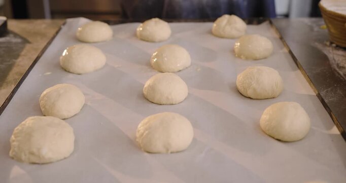 Diverse female pastry cooks brushing wash after shaping dough in bakery, readying for baking