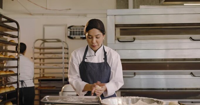 Diverse female bakers in jackets shaping dough newcomer bringing tray urging lining pans for baking