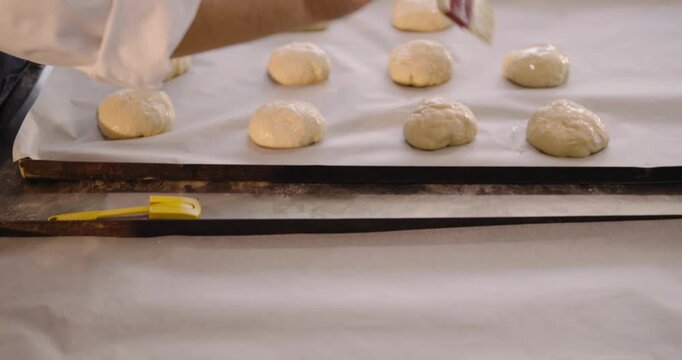 As brush touches, rounds are being glazed divided shaped dusted and staged for proofing at counter