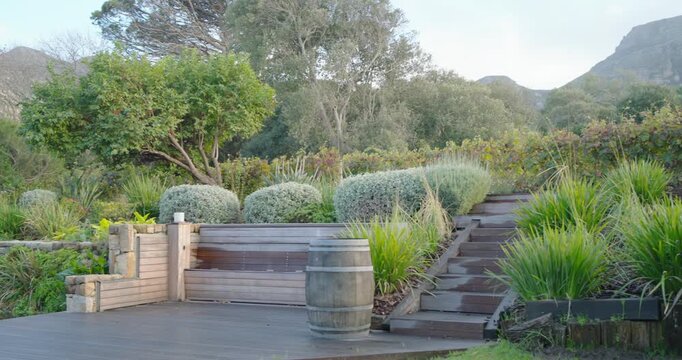 Camera is starting rightward pan from stone-edged pond to reveal wooden deck, bench and steps