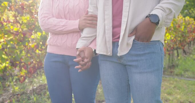 African American couple starting with linked hands, walking among vines, pink sweater, sharing walk
