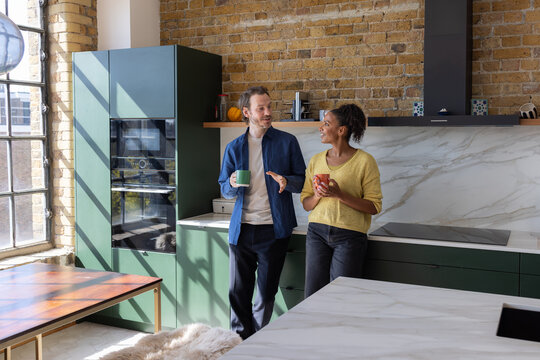 Multiracial couple enjoying coffee in their first home together